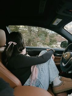 a woman sitting in the driver's seat of a car with her feet on the steering wheel