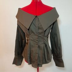 a woman's green jacket on a red mannequin head stand next to a white wall