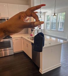 a hand is holding a car key in a kitchen with an island and stove top