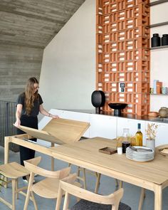 a woman standing in front of a wooden table