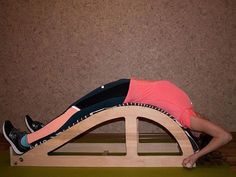 a woman in pink shirt laying on top of a wooden bench