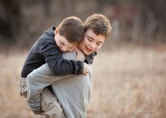 two young boys hugging each other in a field