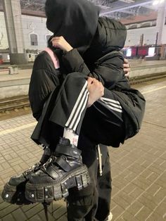 a person in a black jacket and skis is covering his face with a hood