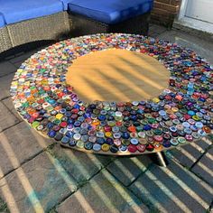 a table made out of bottle caps sitting on top of a brick sidewalk next to a blue couch