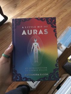 a person holding up a book about auras