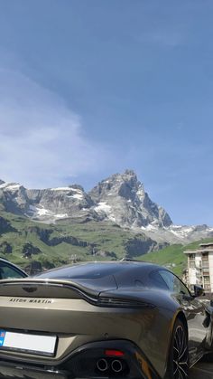 two sports cars parked in front of a mountain