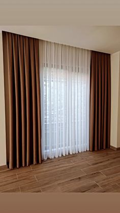 an empty room with wooden floors and curtains