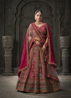 a woman in a red and gold bridal gown standing with her hands on her hips