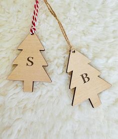 two wooden christmas trees with the letter s and b hanging from strings on a white furnishing