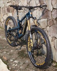 a blue and yellow bike parked next to a stone wall