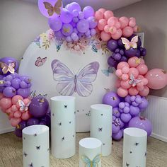 balloons and candles are arranged in front of a butterfly balloon arch for a birthday party