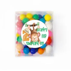 a box filled with lots of colorful candies next to a sticker that says thanks for swinging by