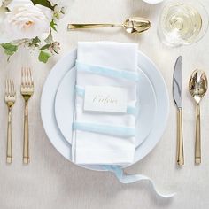 a place setting with silverware, napkins and flowers on a white table cloth