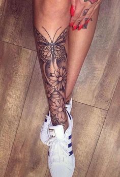 a woman's legs with tattoos and flowers on them, sitting on the floor