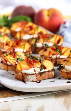 several pieces of bread on a white plate with peaches and other fruit in the background