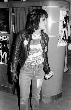 a woman standing next to a trash can in a room with posters on the wall