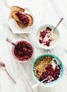 three bowls filled with oatmeal and cranberry toppings on top of a marble counter