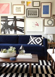 a living room with blue couches and pictures on the wall above it's coffee table