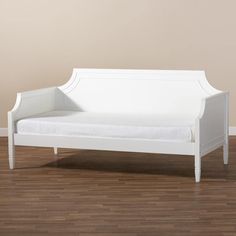 a white daybed sitting on top of a hard wood floor next to a wall