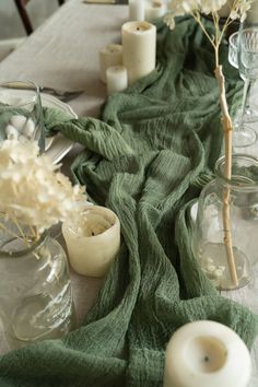 the table is set with candles, vases and green cloth on it's edge