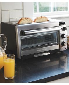 toaster oven with two slices of bread on top and orange juice next to it