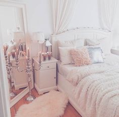 a bedroom with white bedding and candles on the nightstands in front of it