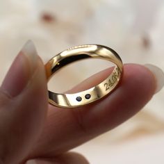 a close up of a person's hand holding a gold ring with black dots