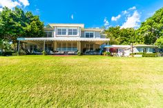 a large white house sitting on top of a lush green field