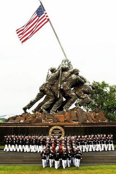 a group of people standing in front of a statue with an american flag on it