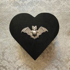 a heart shaped object with a bat on it's side, hanging from the wall