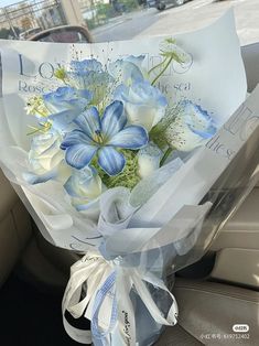 a bouquet of blue and white flowers in the back seat of a car