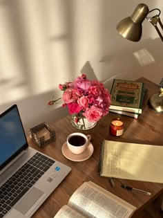 a laptop computer sitting on top of a wooden desk next to a cup of coffee