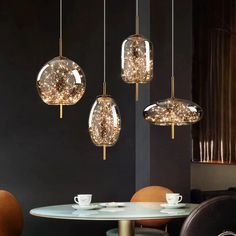 three lights hanging from the ceiling above a table with two cups and saucers on it