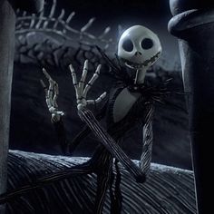 a skeleton dressed as jack skellingy holding two hands up in front of a dark background