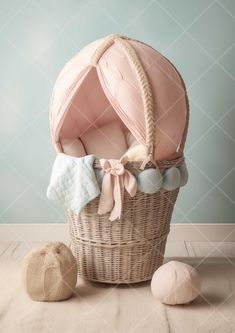 a baby's pink blanket in a wicker basket next to two balls on the floor