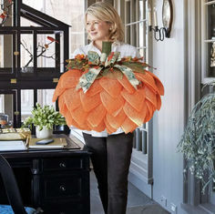 a woman is walking down the hallway carrying a large pumpkin decoration