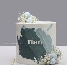 a white cake decorated with blue and grey icing, flowers and eggs on top