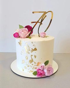 a white cake with pink and gold flowers on it's side, sitting on a table