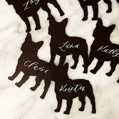 six dog silhouettes with names on them sitting on a marble counter top in the shape of dogs