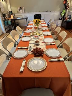 a long table is set with plates and silverware for an elegant thanksgiving dinner in the dining room