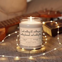 a candle sitting on top of a table next to a string of lights and a guitar