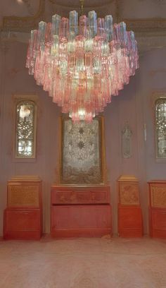 a large chandelier hanging from the ceiling in a room with pink walls and flooring