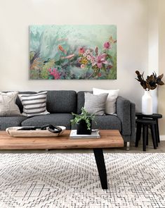 a living room with a couch, coffee table and painting on the wall above it