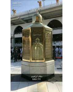 the golden statue is on display in front of an open air area with people standing around it