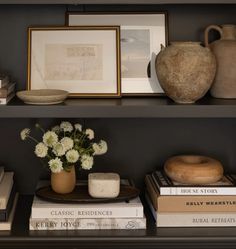 books, vases and other items on a shelf in a room with black walls