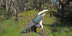 a woman is doing yoga in the woods with her arms stretched out and head bent