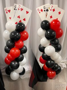 two stacks of playing cards and balloons in front of a white curtain with red and black hearts on them