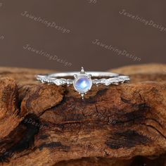 a white gold ring with an opal stone in the center on top of a piece of wood