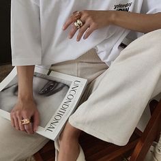 a person sitting on a chair with a book in their lap and wearing a ring