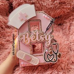 someone is holding up a pink house shaped brooch with the word betty on it